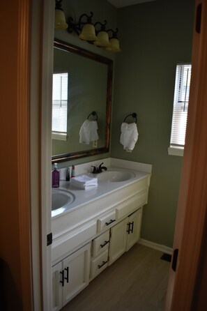A bathroom with a white vanity, a large mirror, and a window with blinds. - Gorgeous 3 Bedrooms with 3 baths by Zona Rosa (Kansas City)