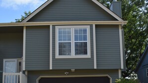 A two-story house with a dark gray exterior, a garage, and a small porch with a white railing.