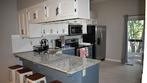 A kitchen with white cabinets, a granite countertop, and a stainless steel refrigerator.