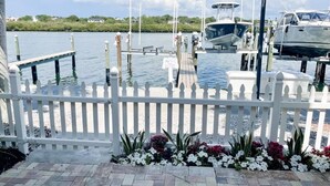 Una marina con barche ormeggiate, un recinto bianco con steccati e un vialetto lastricato con fiori.