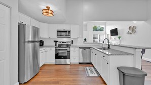 A modern kitchen with white cabinets, stainless steel appliances, and a wooden floor. - Spacious, 3 bedroom home, finished basement on quiet court (St. Peters)