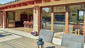 Patio esterno con tavolo in legno, sedie e una lanterna.