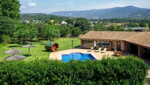 Una casa con piscina, area salotto esterna e vista sulle montagne.