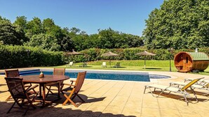 Una piscina con sillas de descanso y una estructura de barrica de madera.