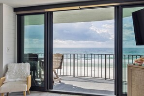 Uma varanda com vista para o oceano, uma cadeira e uma mesa.