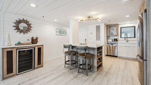 A modern kitchen with a central island, bar stools, a built-in dishwasher, and a refrigerator.