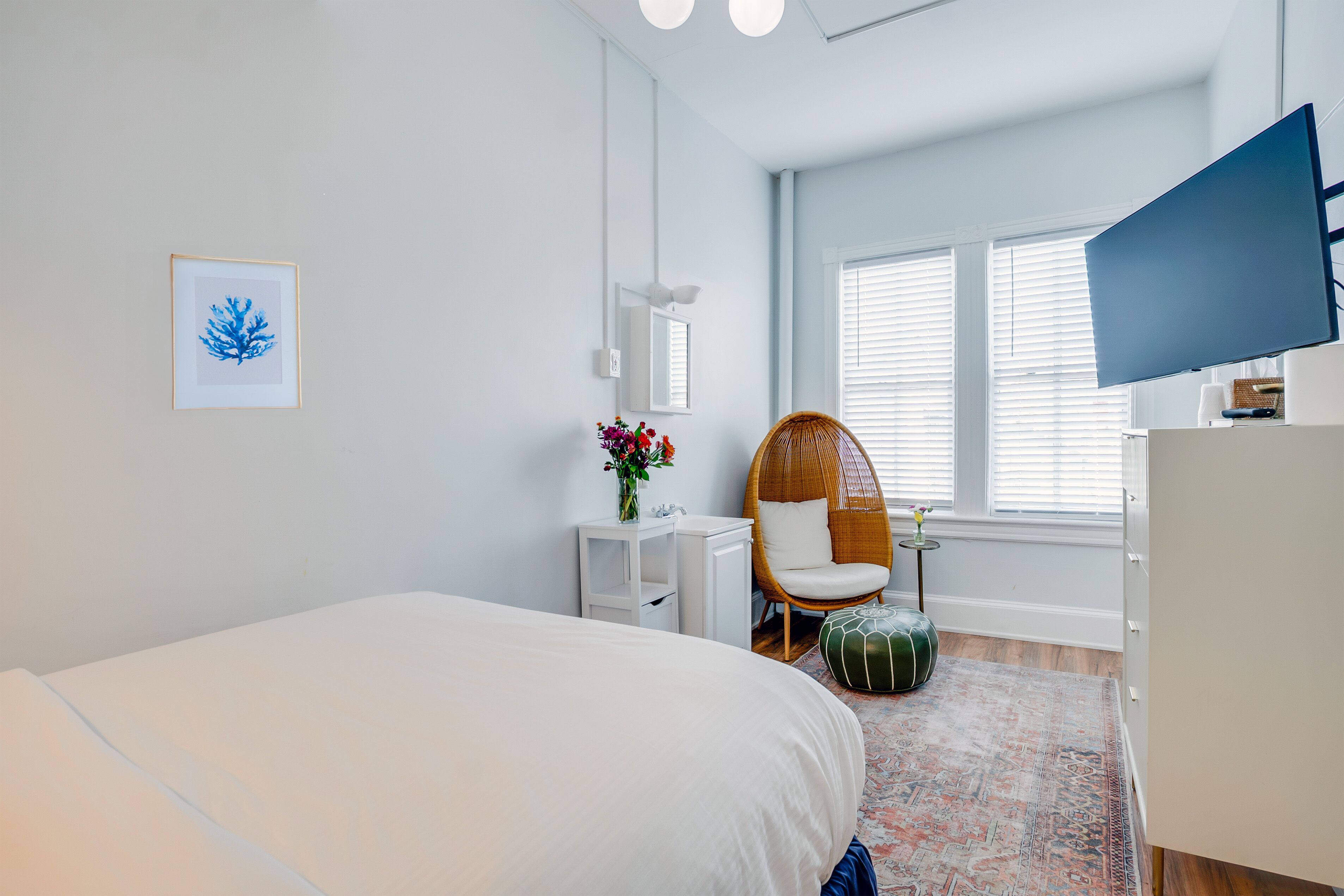 Un dormitorio moderno con cama, una silla, un escritorio y una televisión.