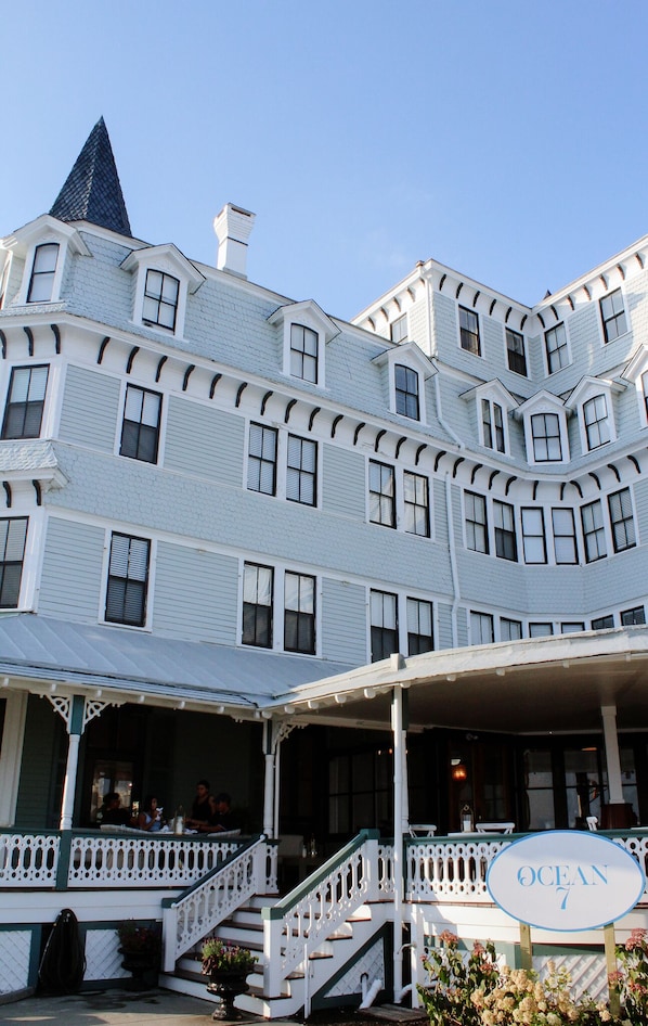 A large, multi-story building with a prominent corner tower, a covered porch, and a sign reading "OCEAN 7". - The Inn of Cape May (Cape May)