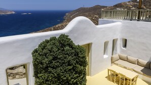 A white-washed building with a view of the sea, a small garden, and a seating area. - Beautiful Villa Isabella (Mykonos)