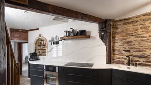 Una cocina moderna con encimera de mármol, horno empotrado y pared de piedra.