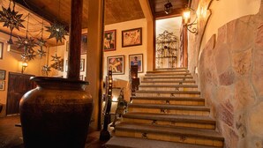 A staircase with stone walls and tiled steps, leading to a door with a wrought iron gate.