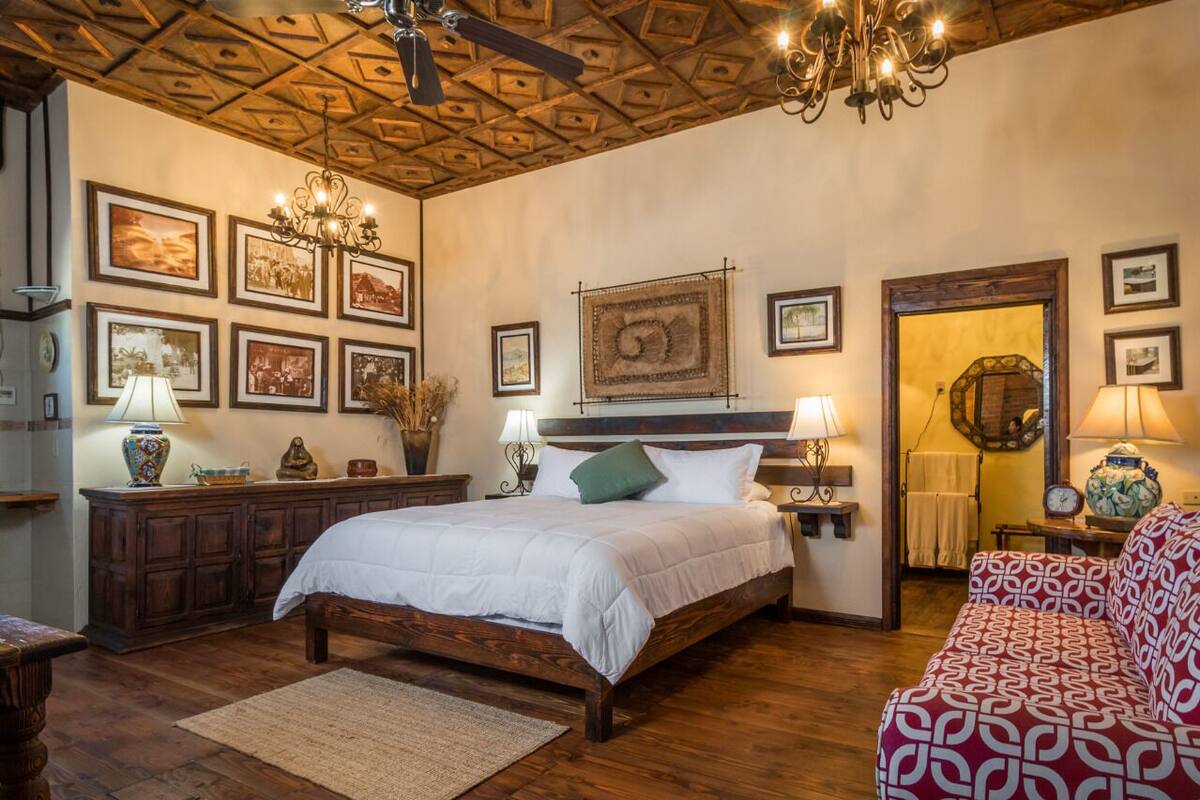 A bedroom with a wooden bed, a wooden ceiling, and framed pictures on the walls.
