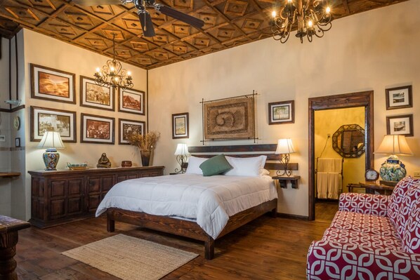 Une chambre avec un lit en bois, un plafond en bois et des tableaux encadrés accrochés aux murs.