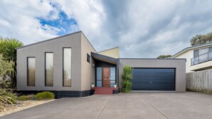 Ett modernt hus i två våningar med garage, stora fönster och en välskött uppfart.