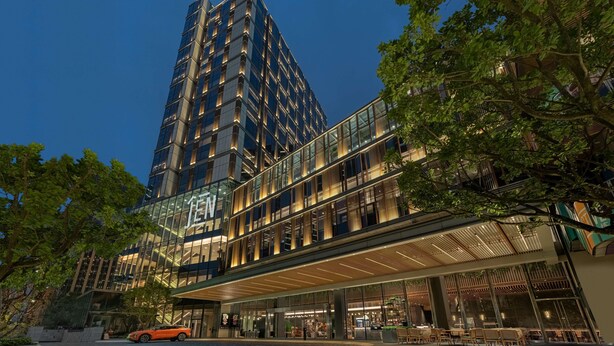 A modern hotel with a prominent 'IEN' sign, multiple floors, and a covered outdoor area with seating.