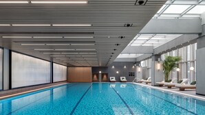 Ein Hallenbad mit deutlichen Bahnen, moderner Beleuchtung und Liegebereichen mit Sitzmöglichkeiten.