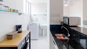 A modern kitchen with a coffee maker, washing machine, sink, and microwave.