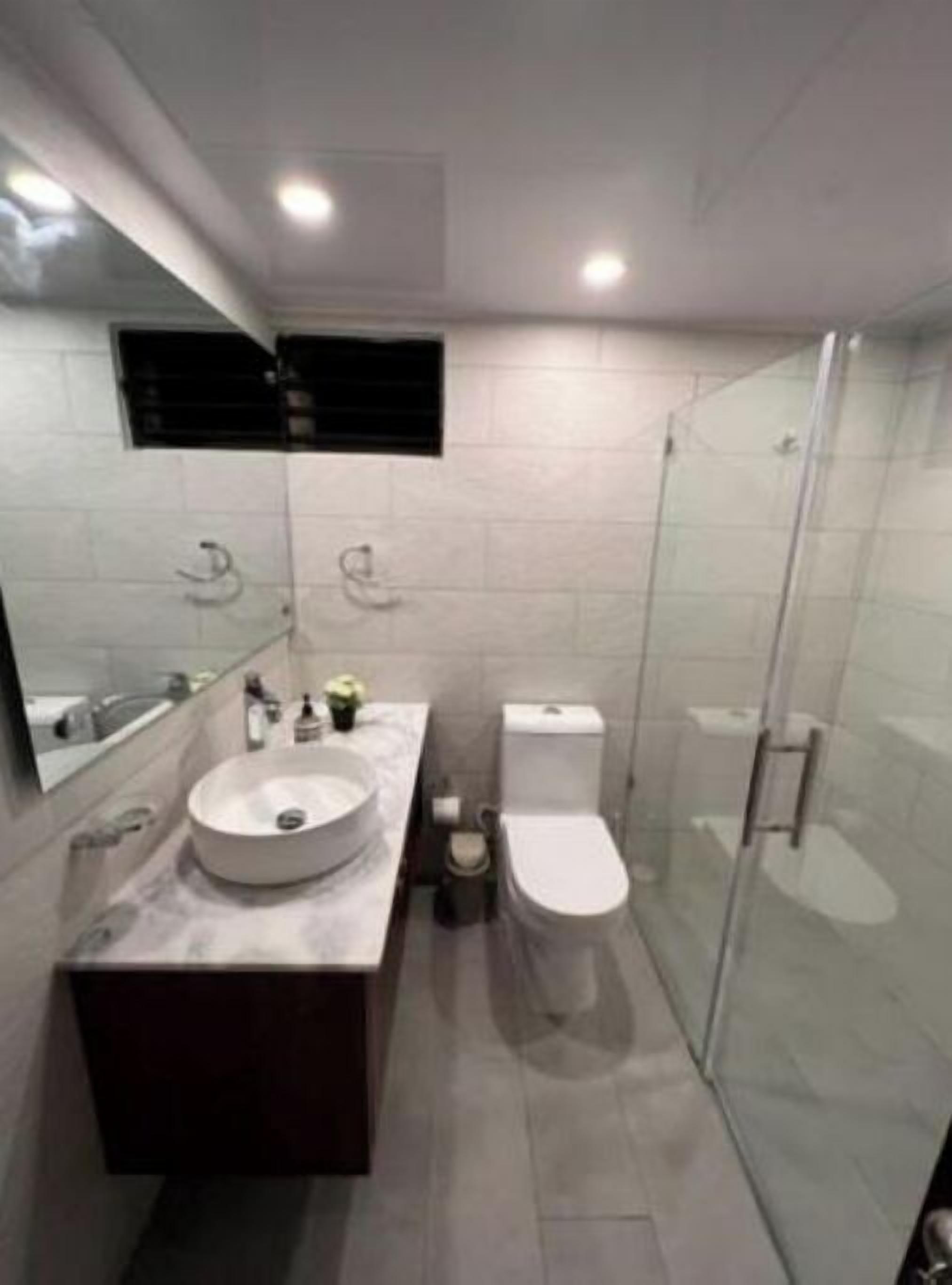 Une salle de bain moderne avec un lavabo rond, des toilettes et une douche à parois de verre.