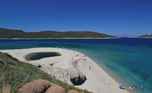 A beach with clear turquoise water, a sandy shore, and a rocky outcrop. - Sea View flat - Marmari village 1hour from Rafina (marmari)