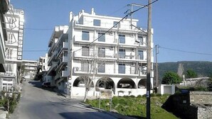 A multi-story building with balconies, a clear sky, and a road in the foreground. - Sea View flat - Marmari village 1hour from Rafina (marmari)