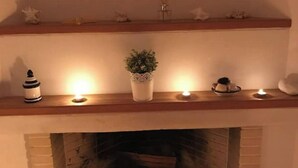A fireplace with a mantel decorated with a potted plant, candles, and a small figurine. - Sea View flat - Marmari village 1hour from Rafina (marmari)