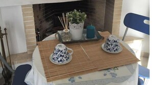 A cozy room with a fireplace, a table set with a teapot and cups, and a chair. - Sea View flat - Marmari village 1hour from Rafina (marmari)