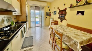 Una cocina con estufa, lavamanos y comedor con sillas y mesa.