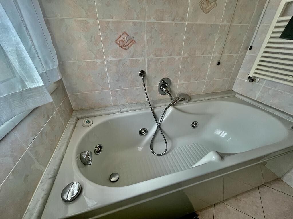 Un baño con una bañera independiente, un cabezal de ducha y un perchero para toallas.