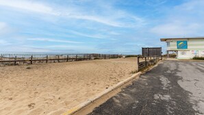 A beachside property with a sandy area, a wooden fence, and a building with a sign. - Apartment with Private Terrace & Shared Garden (Mimizan)