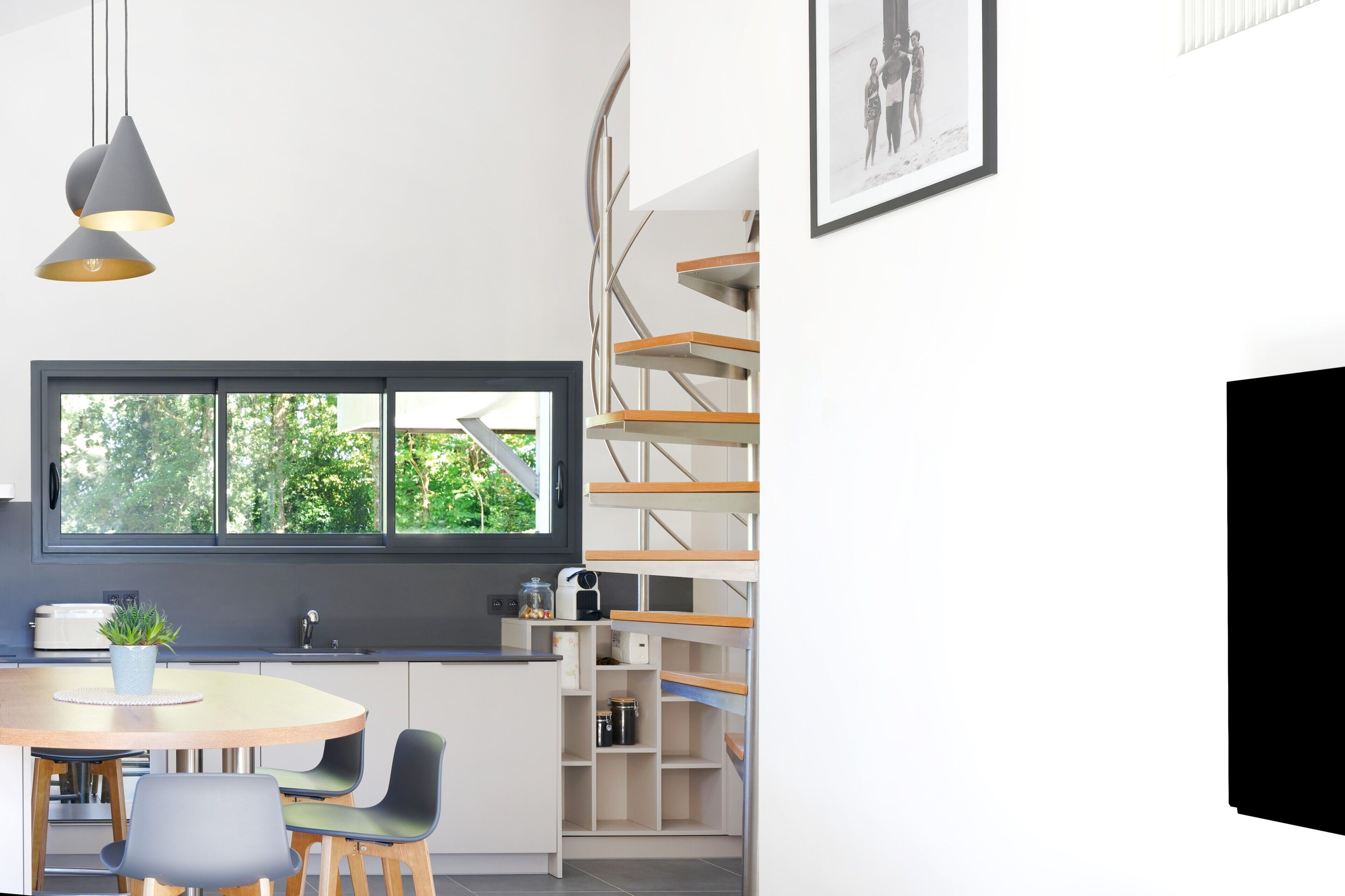 Una cocina moderna con ventana, estanterías empotradas y un comedor con sillas.