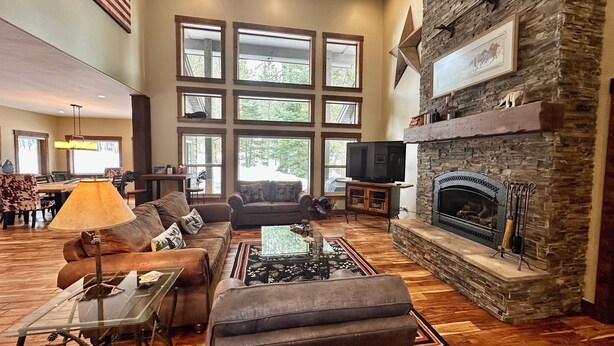 A spacious living room with a stone fireplace, large windows, and a cozy seating area. - The Great Escape at Heavens Gate A/C, fire pit, The Great Escape at Heavens Gate (McCall)