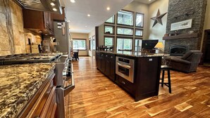 A spacious kitchen with a large island, dark cabinetry, and a stone accent wall. - The Great Escape at Heavens Gate A/C, fire pit, The Great Escape at Heavens Gate (McCall)