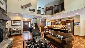 A spacious living area with a fireplace, a large brown leather sofa, a glass coffee table, and a staircase leading to an upper level. - The Great Escape at Heavens Gate A/C, fire pit, The Great Escape at Heavens Gate (McCall)