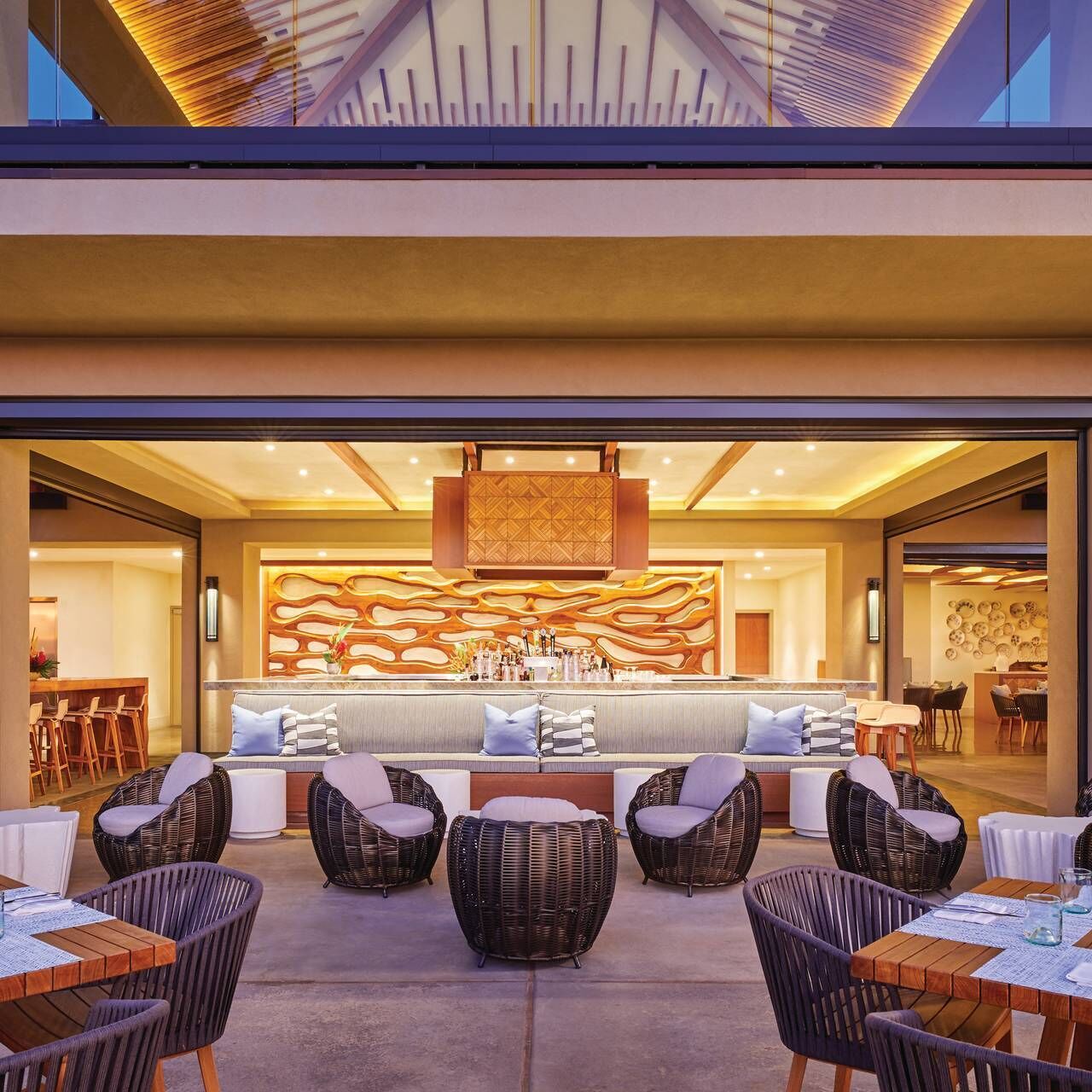 A modern outdoor seating area with wicker furniture and a central sofa.