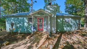 A small, single-story house with a red door and a 'Welcome' sign above the entrance. - Renovated Cottage! Overlooks Dale Hollow! (Byrdstown)