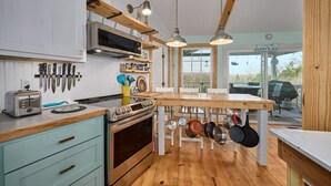 A kitchen with wooden cabinets, a stove, a toaster, and hanging pots. - Renovated Cottage! Overlooks Dale Hollow! (Byrdstown)