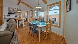 A cozy interior with a wooden dining table, blue chairs, and a kitchen area with a microwave and utensils. - Renovated Cottage! Overlooks Dale Hollow! (Byrdstown)