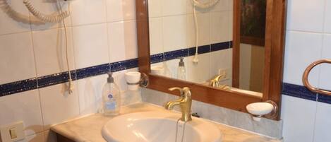 A bathroom with a white sink, wooden vanity, and a mirror with lights.
