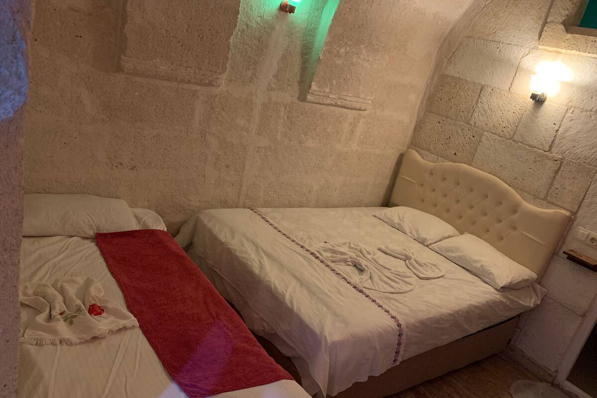 A small, cozy room with two beds, a red towel, and a wall-mounted light.