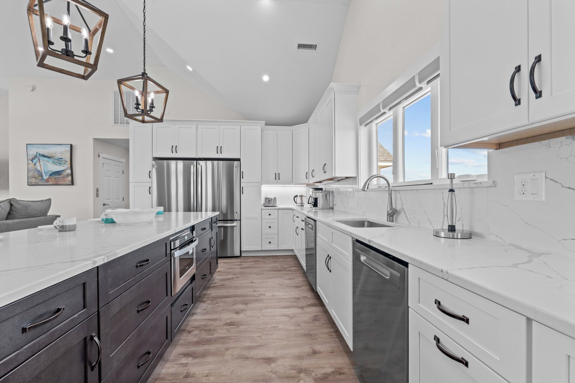 A modern kitchen with white cabinetry, stainless steel appliances, and a marble countertop.