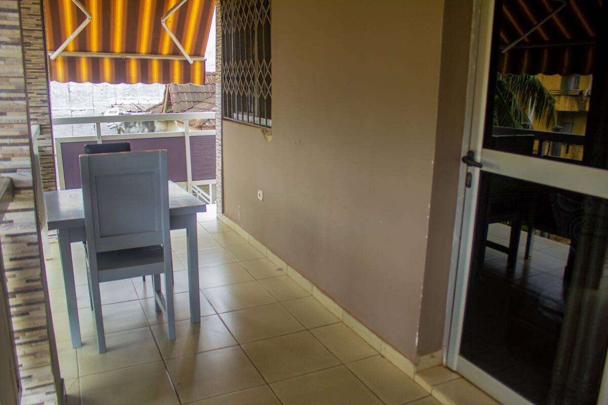 A small dining area with a table and chairs, a window with a striped curtain, and a door leading to another room.