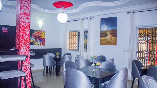 A dining area with a table and chairs, a red pillar, and artwork on the walls. - Residences Hydlyss (Abidjan)