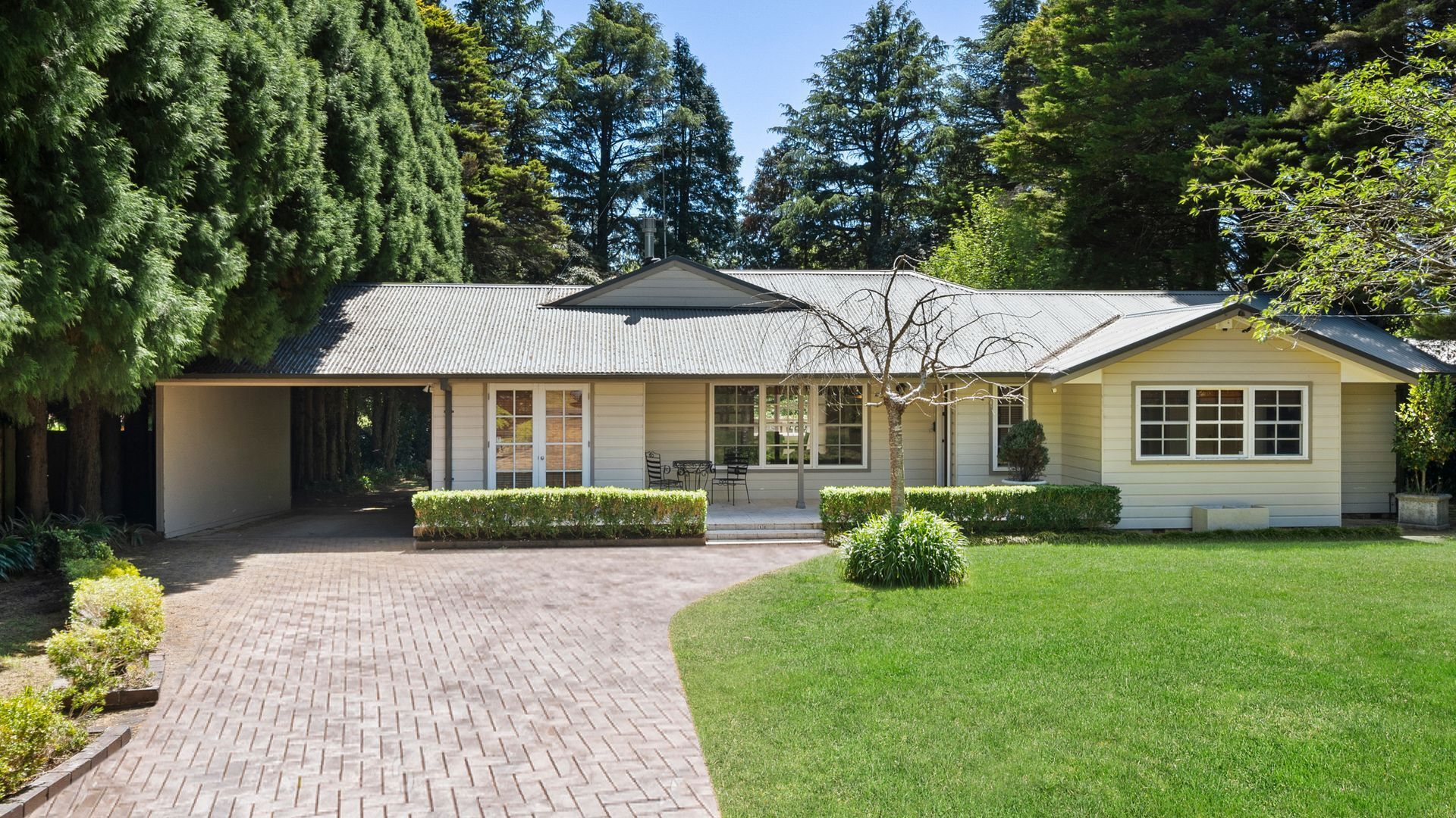 A single-story house with a covered porch, a brick driveway, and a well-maintained lawn.