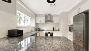 Een moderne keuken met een granieten aanrecht, roestvrijstalen apparatuur en een raam voor daglicht.