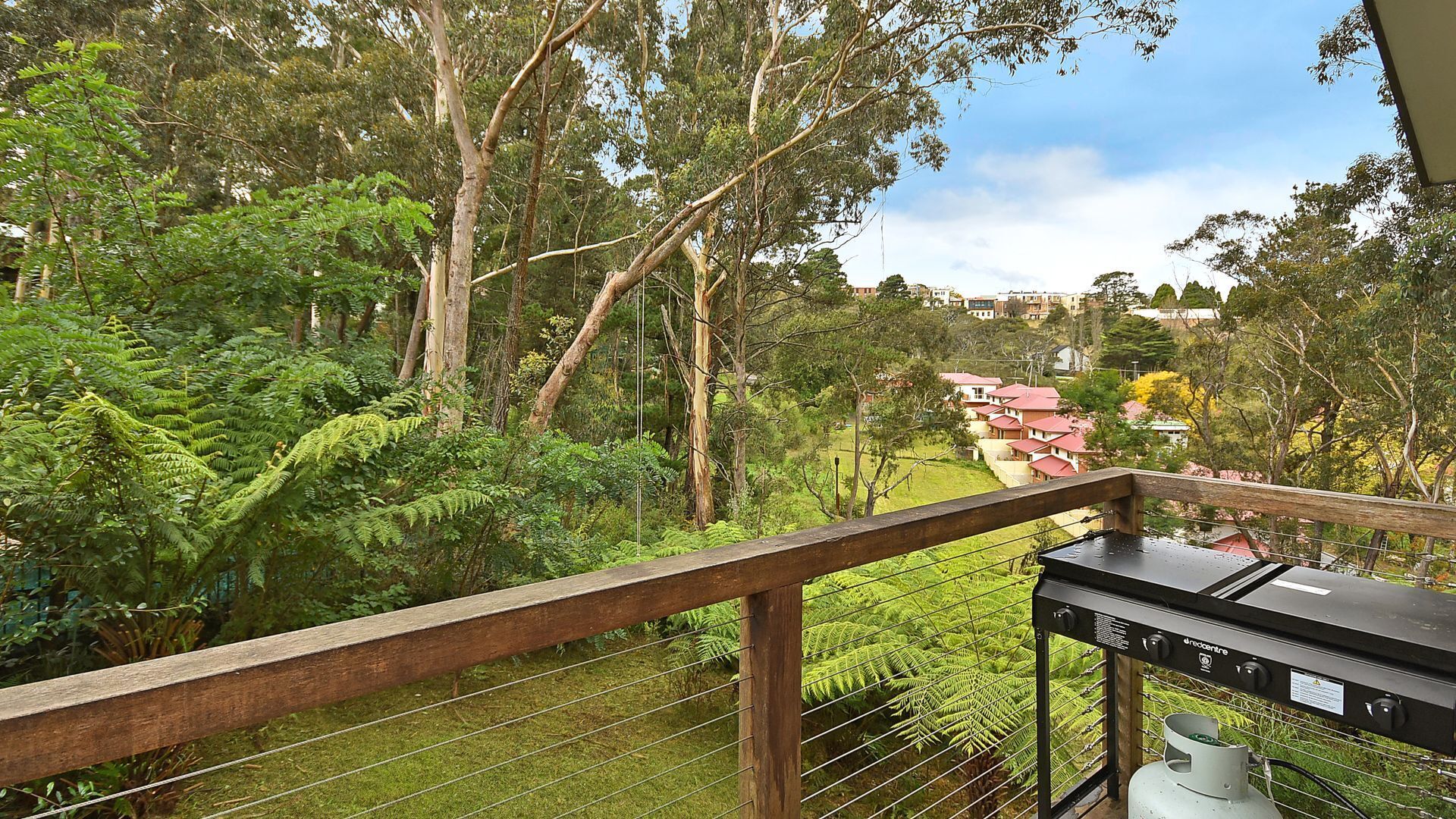 Un balcón con vista a un jardín exuberante y una zona residencial.