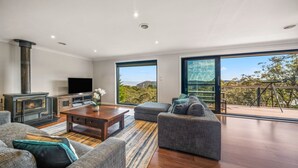 Ein modernes Wohnzimmer mit Kamin, Flachbildfernseher, Couchtisch und Sofa.
