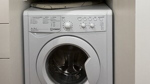 A washing machine with a control panel and a shelf above it holding folded towels and toiletries. - Le Haut Marais, rue Notre-Dame de Nazareth (Paris)