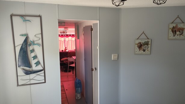 A room with a bed, a door leading to another room, and a wall with a framed picture.