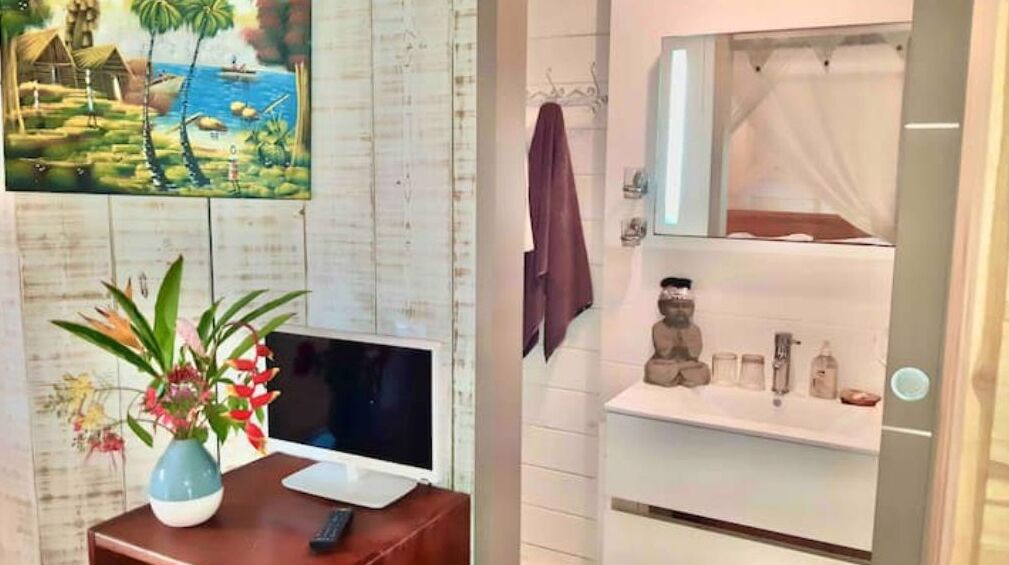 A bathroom with a white vanity, a mirror, and a shelf with toiletries.