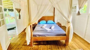 A wooden bed with a canopy, two pillows, and a wooden nightstand. - Villa Gaïa: Bungalow Ti-zen & spa - Parc Tropical (LE DIAMANT)